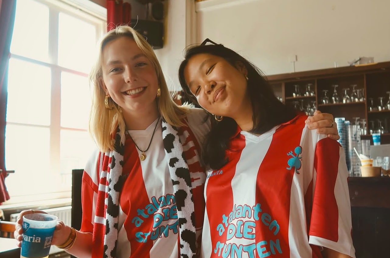 Twee vriendinnen in rood-witte jerseys met tekst 'Atalanten die stunten'