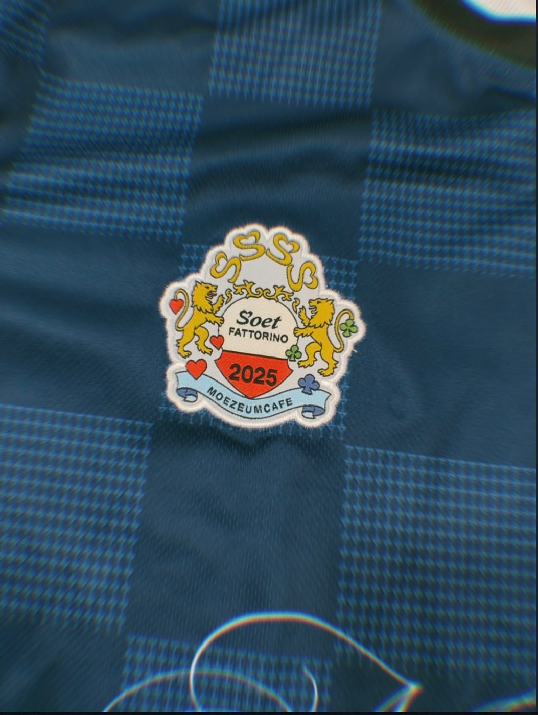 Close-up van geblokte stof en clubembleem van een custom jersey